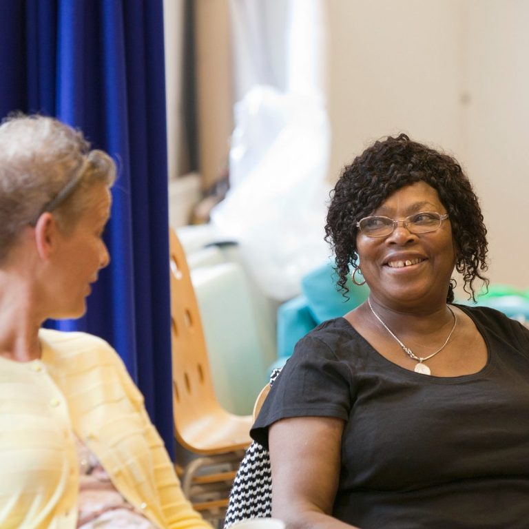 Diverse pair of women looking at each other and smiling in a group session